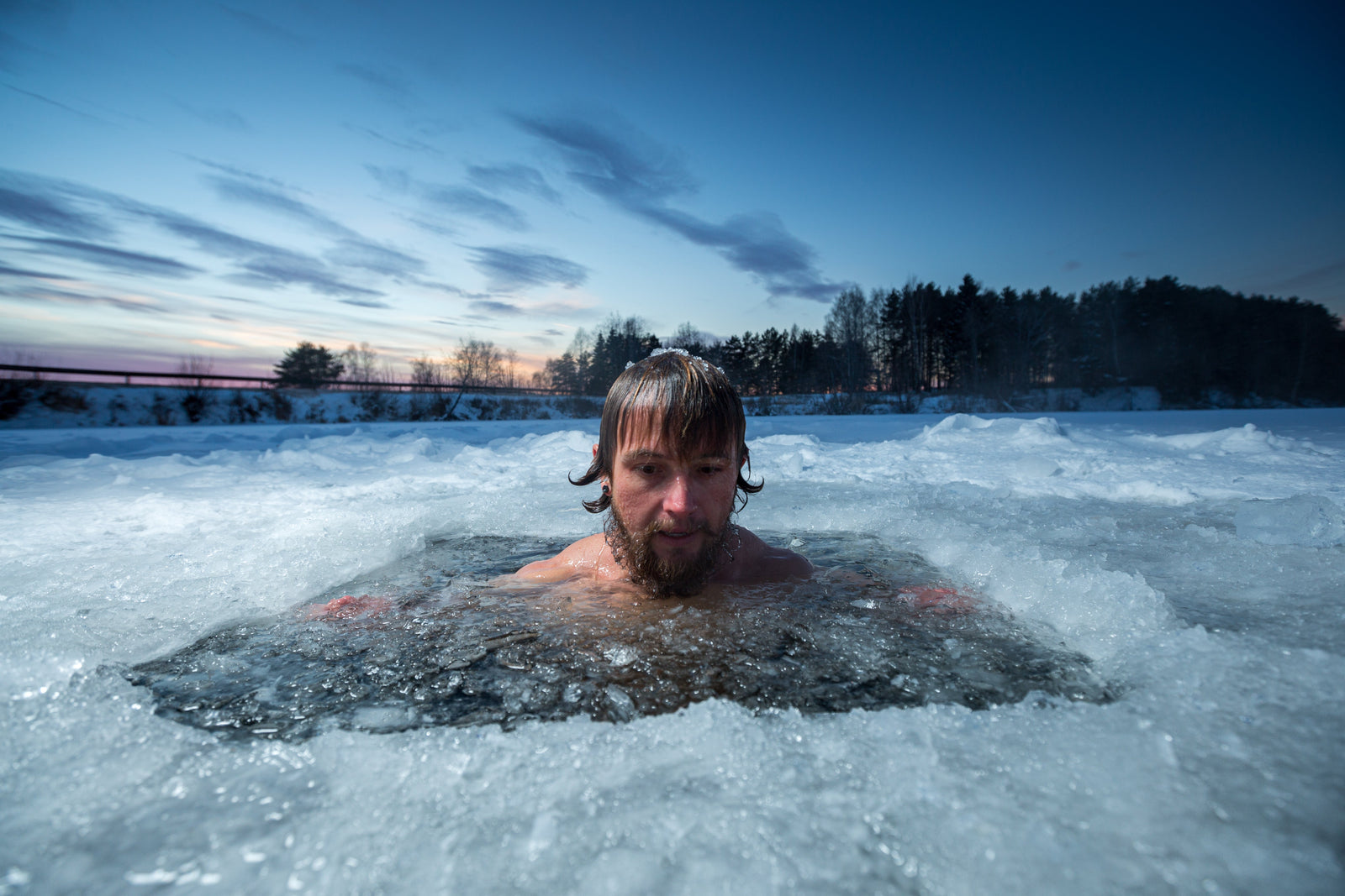 A white man cold plunging in ice in a lake