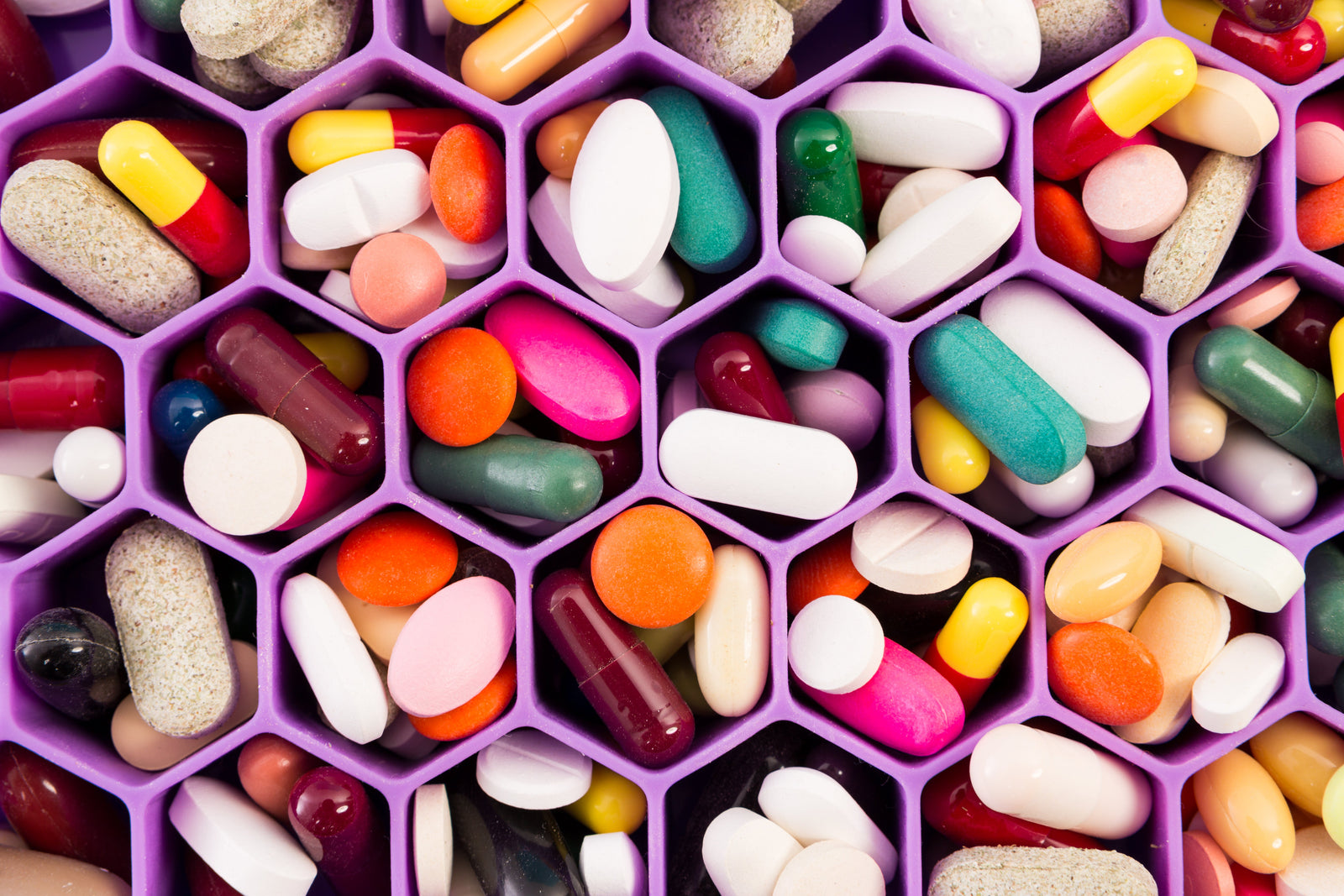 Dozens of supplement pills in a purple supplement container