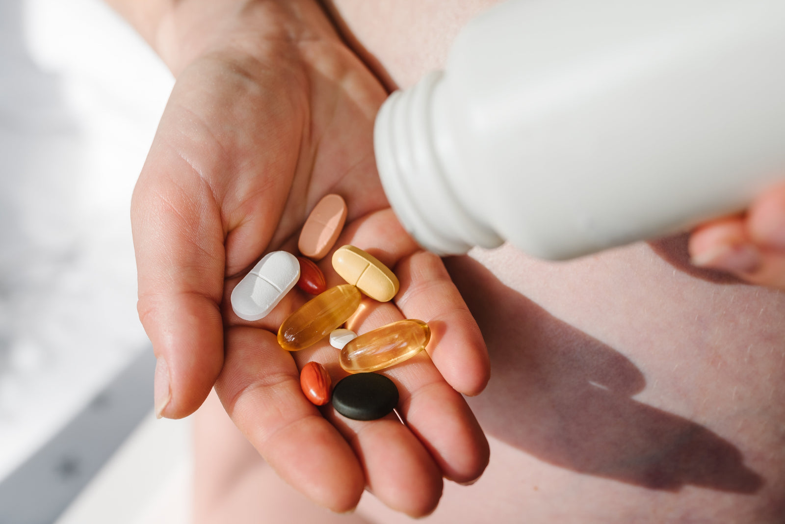 A person holding vitamins in their hand